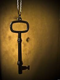 An old-fashioned dark metal key hanging against a dim gold background