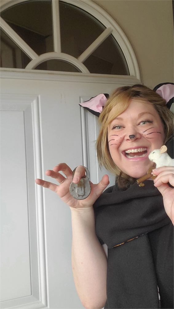 Marcia Blake in cat ears and whiskers, holding a padlock in one hand and a toy mouse with a key in the other